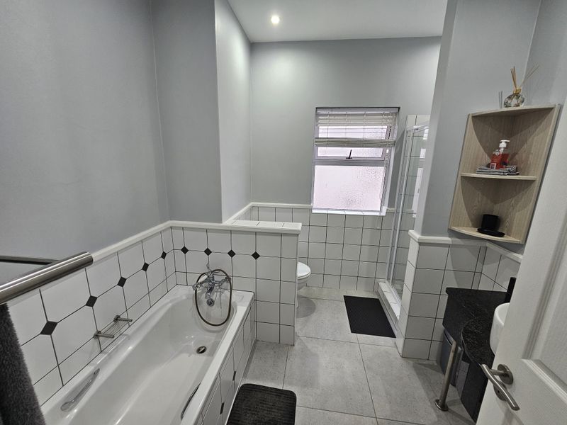 A well-maintained bathroom featuring a built-in bathtub, separate shower enclosure, and a vanity with a stone countertop.