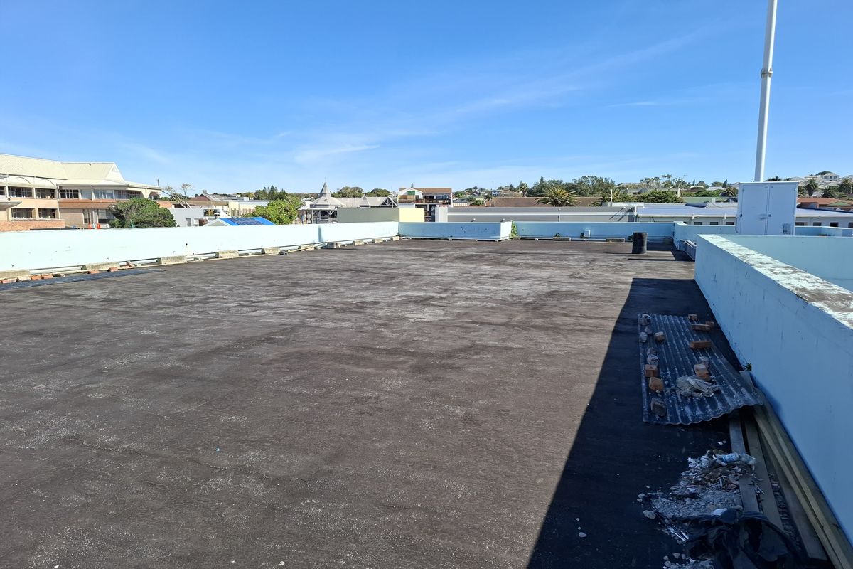 An expansive flat rooftop area with parapet walls, offering potential for development or outdoor utility space with surrounding urban views.