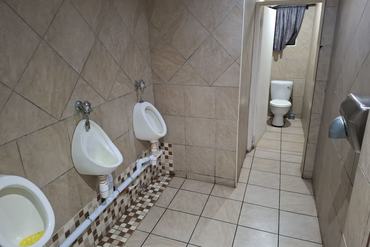 A functional commercial restroom featuring wall-mounted urinals, tiled walls and flooring, and a separate toilet cubicle.