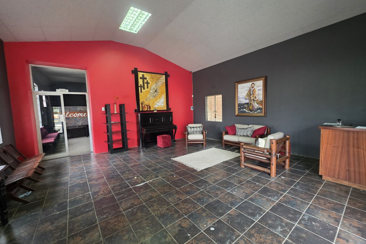 Spacious commercial reception or waiting area featuring dark tiled flooring, high ceilings with recessed lighting, and a distinct red and grey accent wall design.