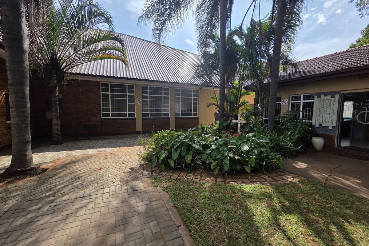 A well-maintained courtyard area featuring paved walkways, established garden beds, and mature palm trees, providing a pleasant outdoor space for the commercial property.
