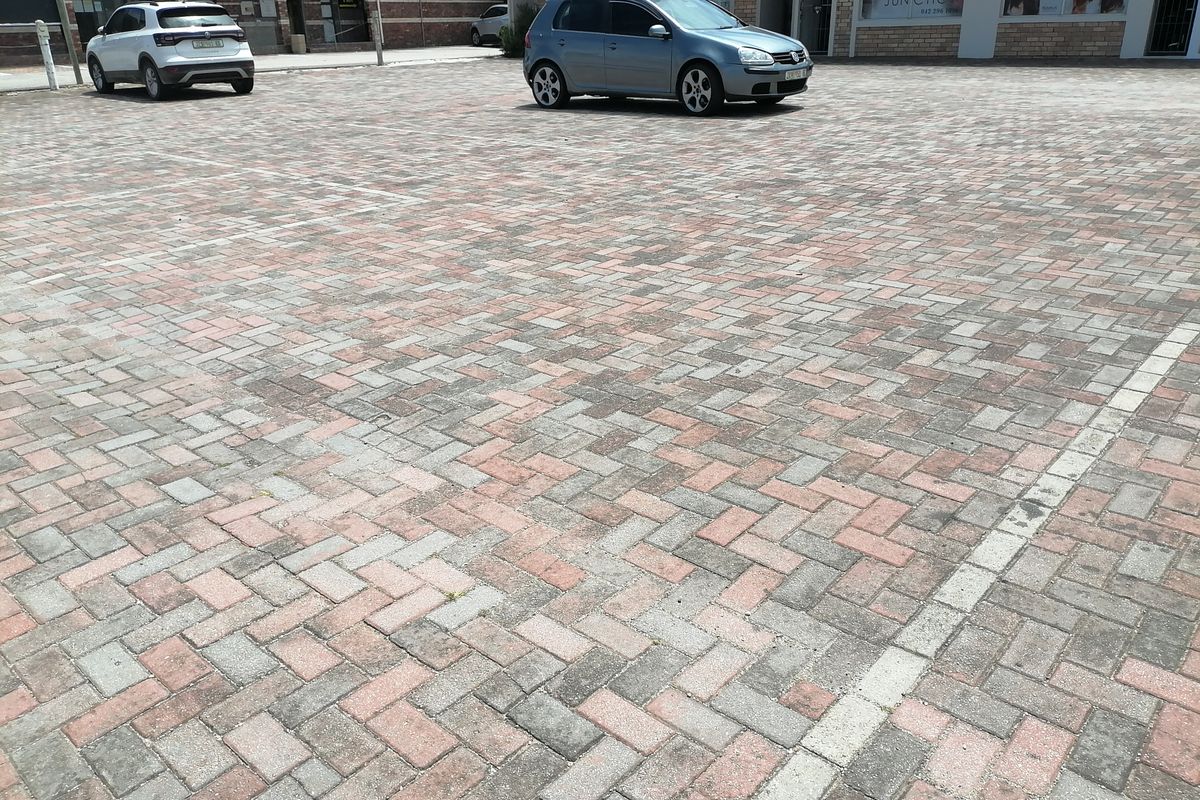 A paved commercial parking area fronting a brick-faced retail building with storefront access.