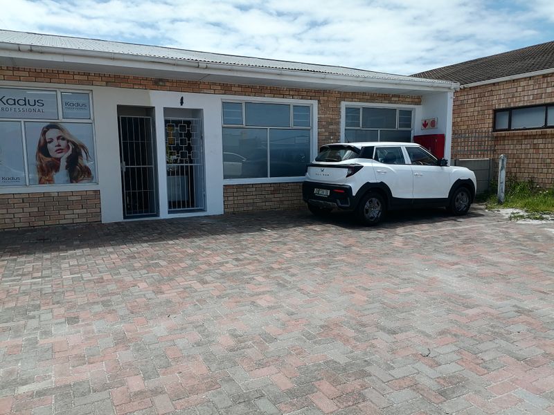Front exterior view of a commercial property featuring a brick facade, paved parking area, and secure entrance with security gates.