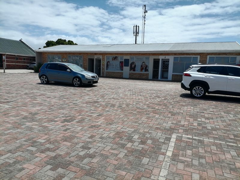 Front exterior view of a commercial property featuring a face brick facade, corrugated metal roof, and paved parking area.