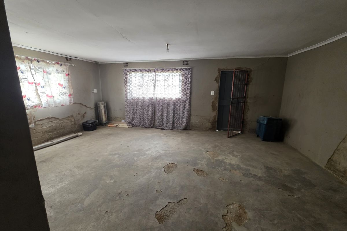 A spacious, unfinished room featuring exposed concrete flooring and raw wall surfaces, offering a blank canvas for renovation and custom interior design.