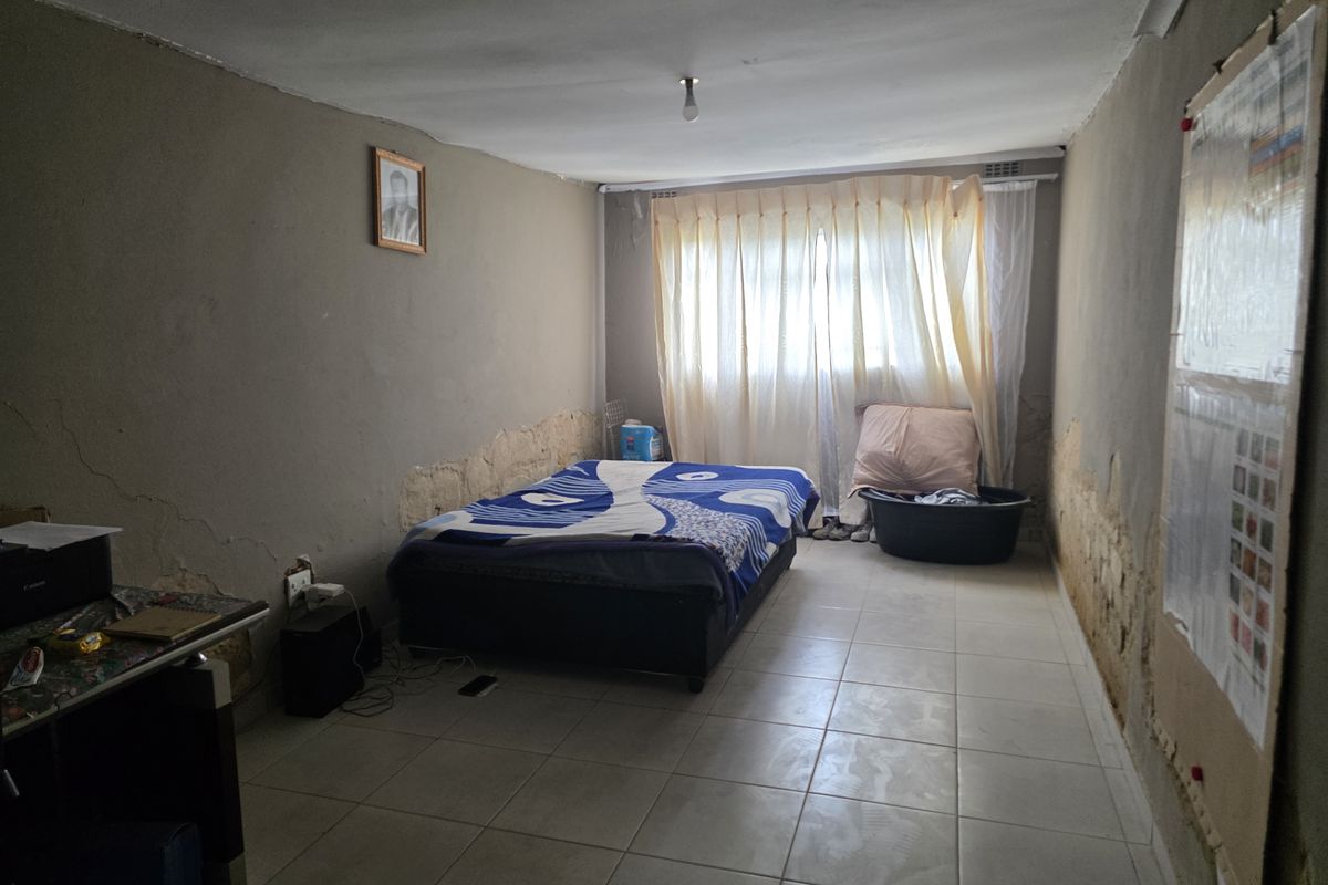 A bedroom featuring tiled flooring and significant wall surface deterioration requiring repair and redecoration.