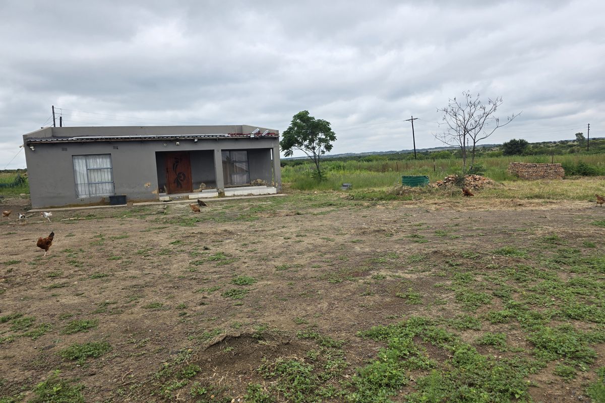 Exterior view of a single-story farm dwelling featuring a covered patio area and surrounding open land.