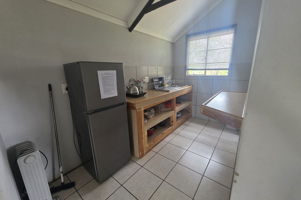 A functional kitchenette area featuring tiled flooring, a stainless steel sink, and custom timber shelving under the counter.