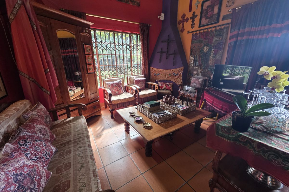A living room featuring terracotta floor tiles, a built-in fireplace, and security bars on the windows.