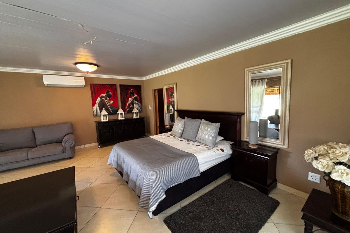 Spacious bedroom featuring tiled flooring, crown molding, and a wall-mounted air conditioning unit.