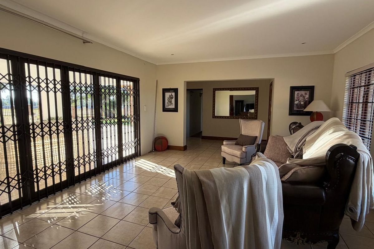 Spacious living area featuring tiled flooring and large sliding doors with security gates, providing access to the outdoor space.