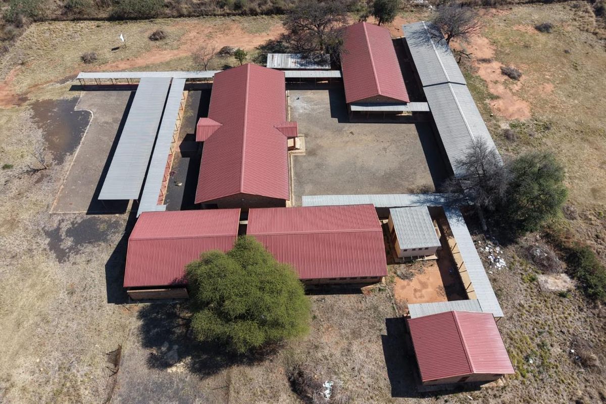 Aerial view of a multi-building office or facility complex featuring corrugated metal roofs and interconnected covered walkways surrounding a central courtyard.