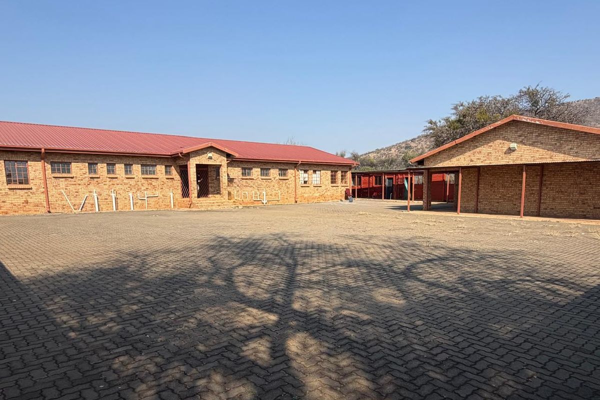 A spacious paved courtyard area featuring face brick office buildings with red corrugated metal roofing and covered walkways.