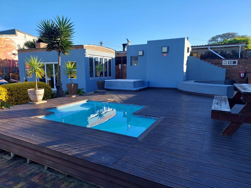 Outdoor entertainment area featuring a swimming pool, built-in spa, and extensive timber decking, set against a blue-painted exterior structure.