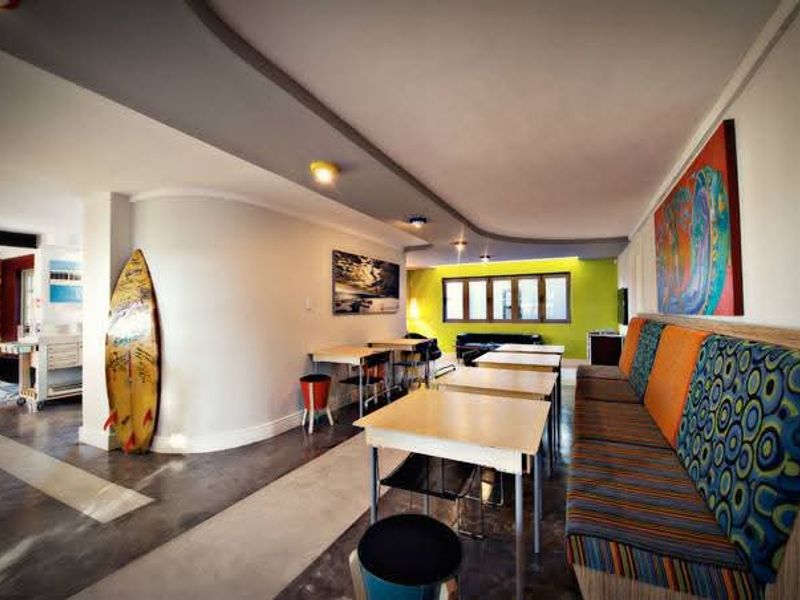 Spacious open-plan living and dining area featuring modern curved architectural details, polished concrete floors, and integrated bench seating.