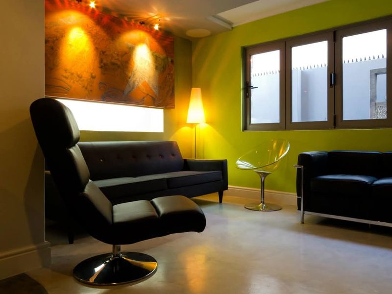 A contemporary living room featuring polished concrete floors, vibrant green walls, and modern recessed lighting, creating a bold and stylish atmosphere.