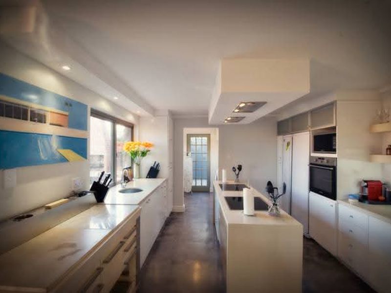 Modern kitchen featuring a central island with integrated hob, built-in oven and microwave, sleek cabinetry, and recessed lighting in a clean, contemporary layout.