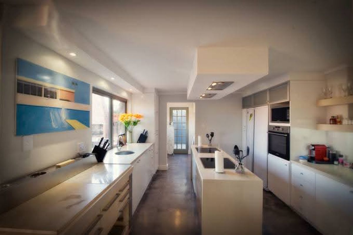 Modern kitchen featuring a central island with integrated hob, built-in oven and microwave, sleek cabinetry, and recessed lighting in a clean, contemporary layout.