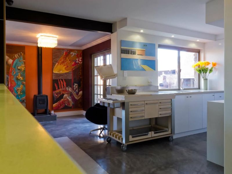 Open plan living and kitchen area featuring polished concrete floors, a modern kitchen island with stainless steel surfaces, and a cozy freestanding fireplace.