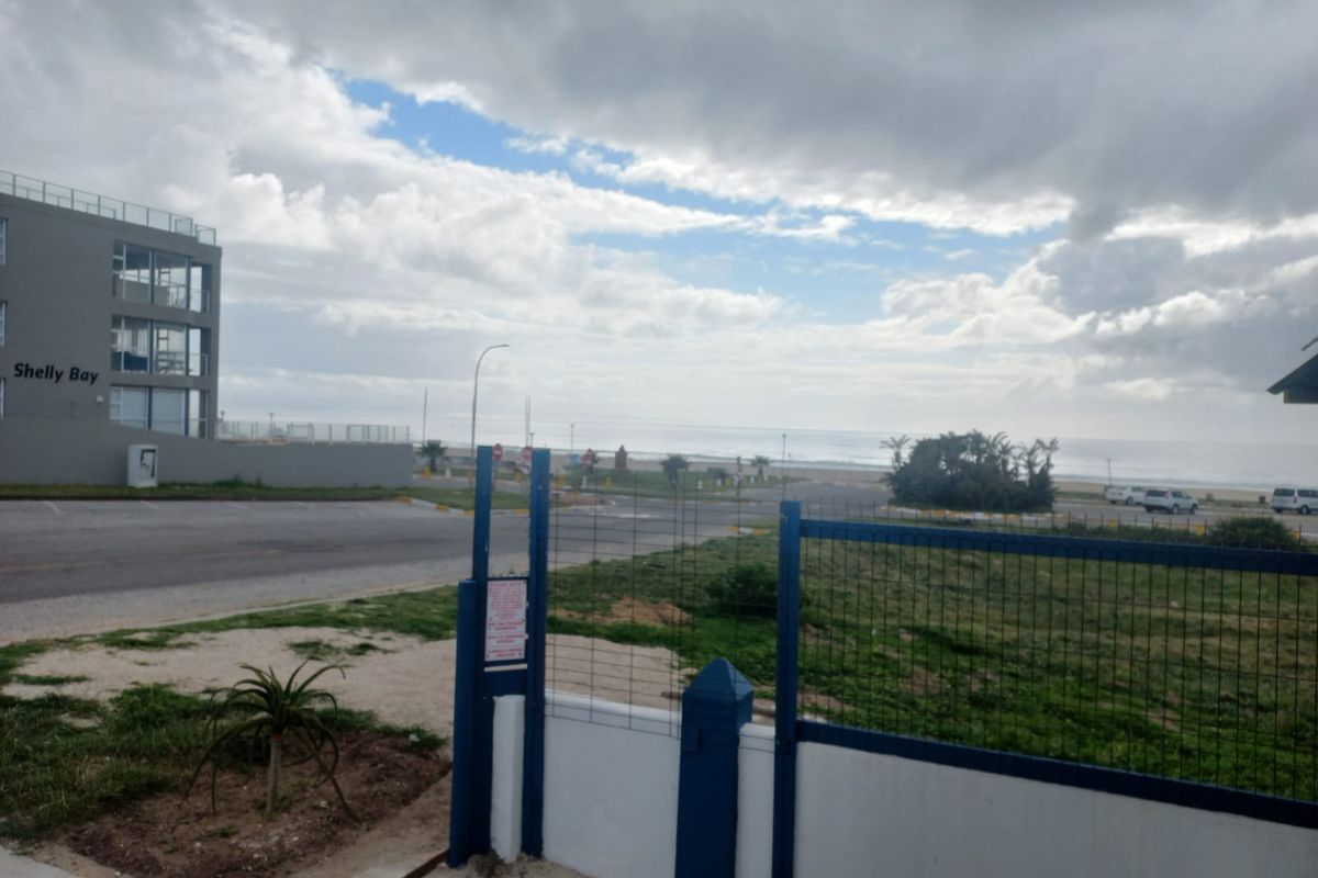 A view of the coastal surroundings and nearby Shelly Bay building, featuring a secure perimeter fence and paved access area.