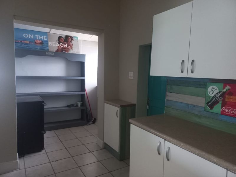 A functional scullery or utility area featuring built-in cabinetry, laminate countertops, and tiled flooring, providing additional storage and workspace.