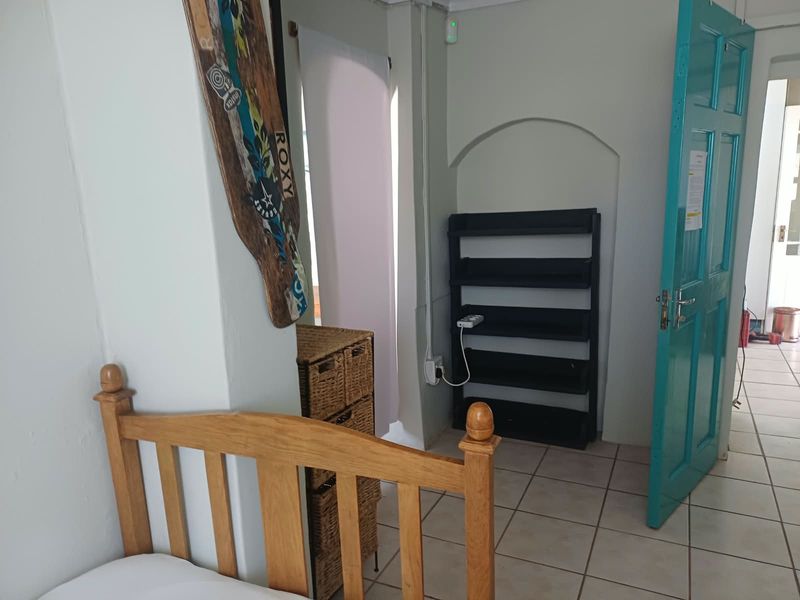 A bedroom featuring tiled flooring, an arched wall niche, and a distinctive teal-painted door, providing access to the adjacent hallway.