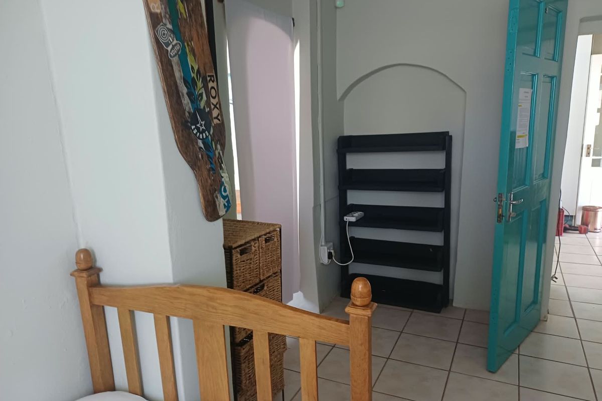 A bedroom featuring tiled flooring, an arched wall niche, and a distinctive teal-painted door, providing access to the adjacent hallway.