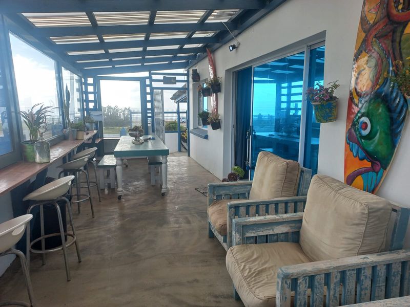 Covered outdoor patio area featuring a built-in bar counter, concrete flooring, and sliding glass door access to the main dwelling.