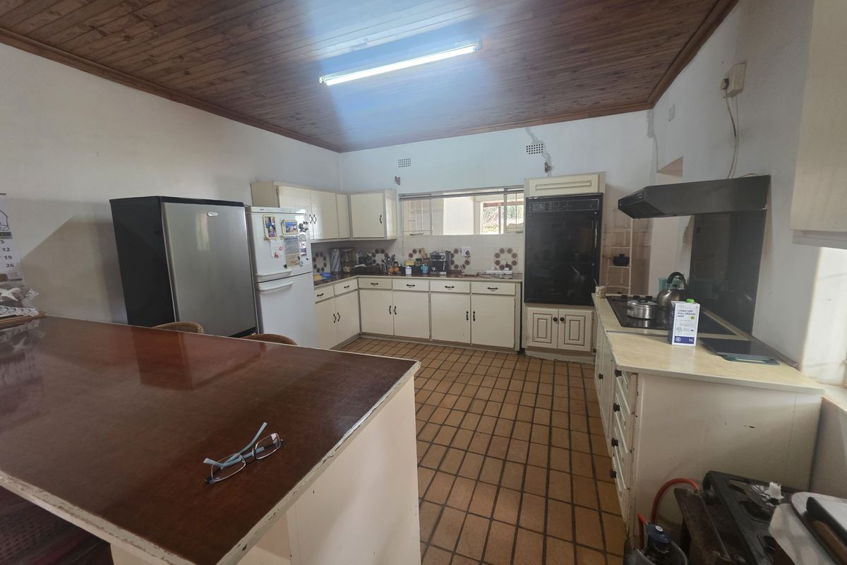 A functional kitchen featuring timber ceilings, tiled flooring, built-in cabinetry, and integrated appliances, offering a traditional layout with ample counter space.