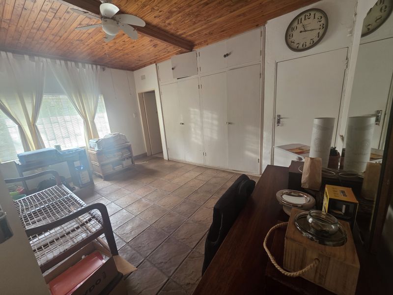 Bedroom featuring a timber ceiling, ceiling fan, tiled flooring, and built-in cupboards.