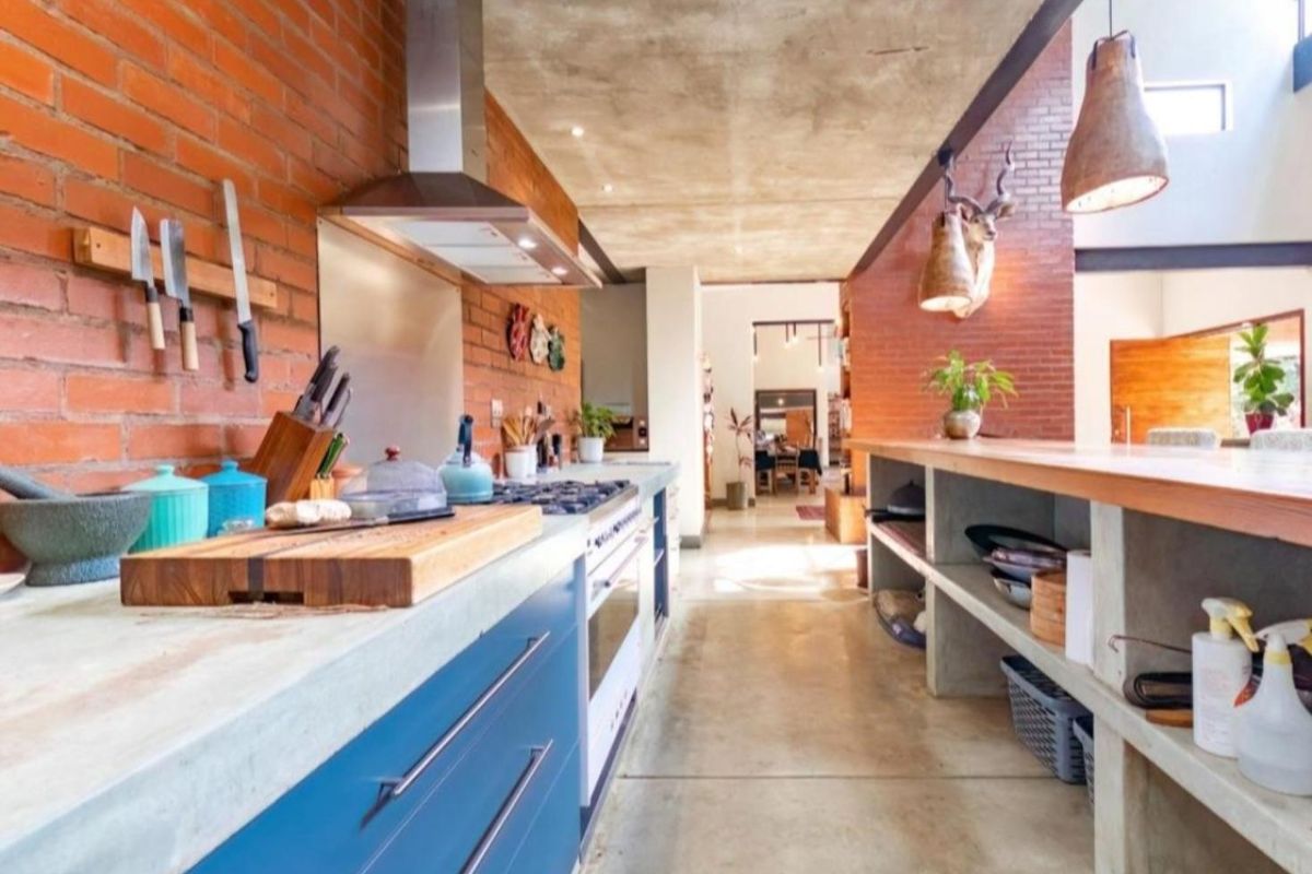 Modern industrial-style kitchen featuring exposed brick walls, polished concrete flooring, concrete countertops, and high-end built-in appliances with an open-plan layout.