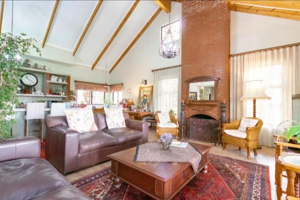 Spacious living room featuring a vaulted ceiling with exposed timber beams and a prominent brick fireplace as a central focal point.