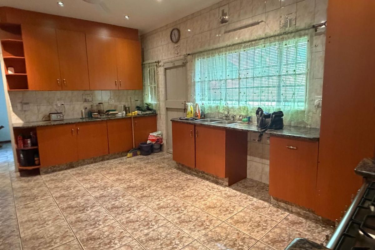Spacious kitchen featuring extensive built-in cabinetry, granite countertops, double basin sink, and tiled finishes throughout.
