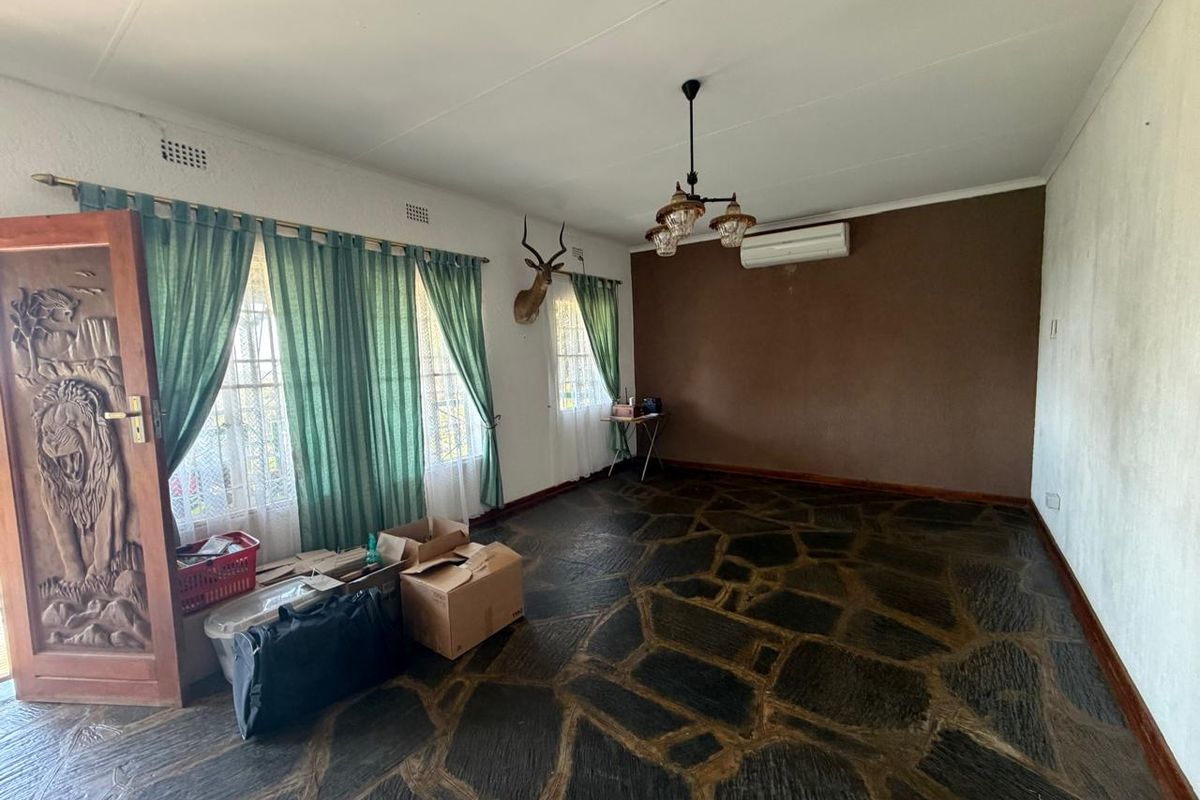 Spacious living room featuring unique stone flooring, a carved wooden entrance door, and a wall-mounted air conditioning unit.