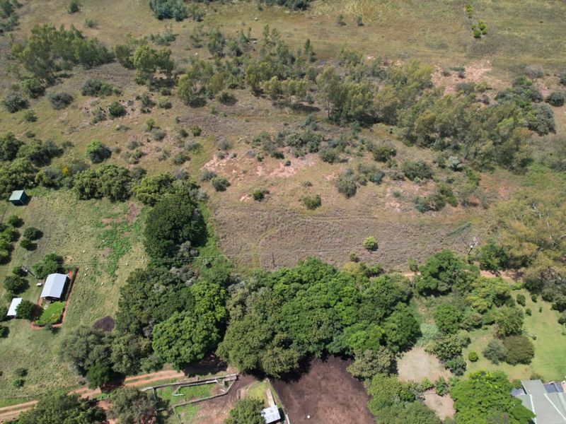 Aerial view of the farm property showcasing expansive open land, mature trees, established outbuildings, and natural landscape features.