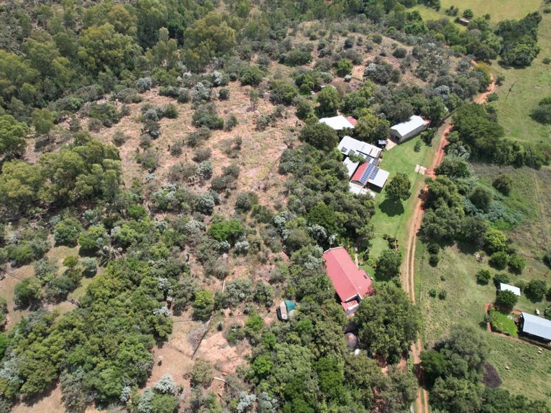 Aerial view of the farm property showing multiple buildings, metal roofing, solar panel installations, and surrounding natural landscape with access roads.