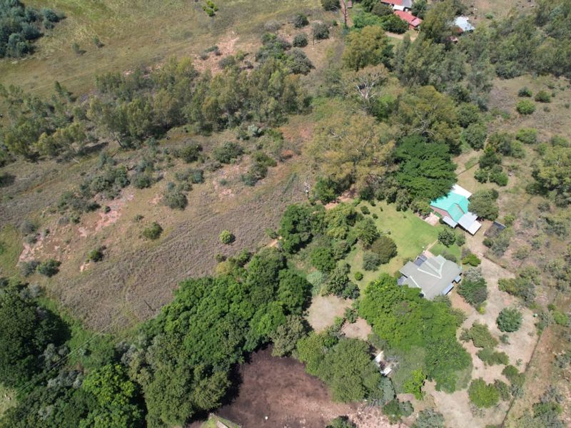 Aerial view of a large rural farm property featuring multiple dwellings, extensive mature vegetation, and open grazing land.