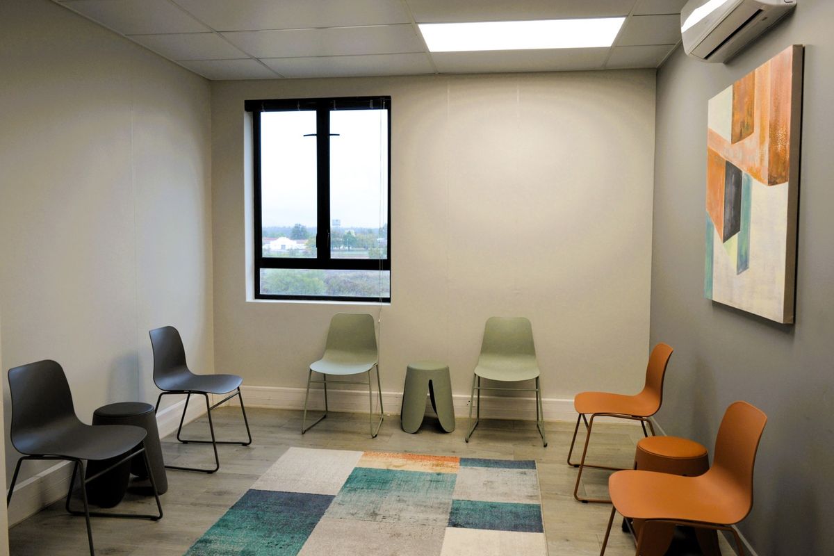 A clean, modern office space featuring a drop ceiling, recessed lighting, split-system air conditioning, and durable laminate flooring.