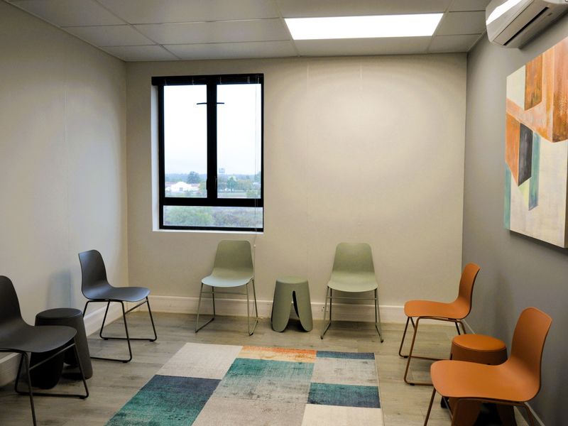 A clean, modern office space featuring a drop ceiling, recessed lighting, split-system air conditioning, and durable laminate flooring.