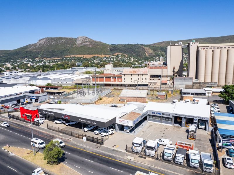 Aerial view of a commercial property featuring multiple warehouse units, paved parking, and street-front access in an industrial area.