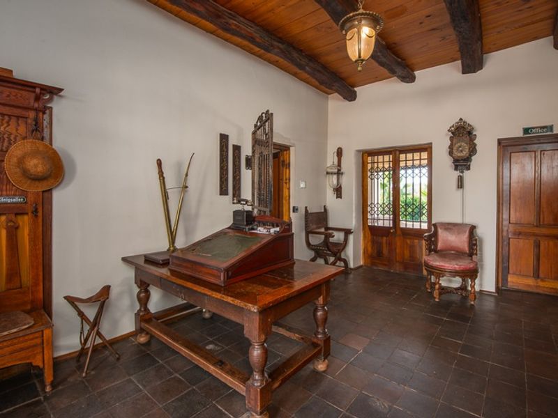 A rustic entrance hall featuring exposed timber ceiling beams, terracotta floor tiles, and traditional timber doors, creating a warm and character-filled welcome area.