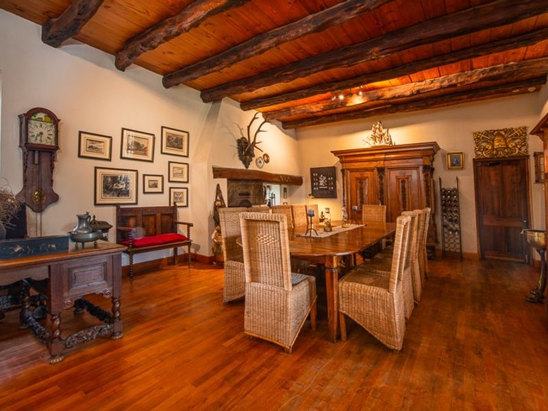 A rustic dining room featuring exposed timber ceiling beams, polished hardwood flooring, and traditional architectural details, creating a warm and character-filled atmosphere.