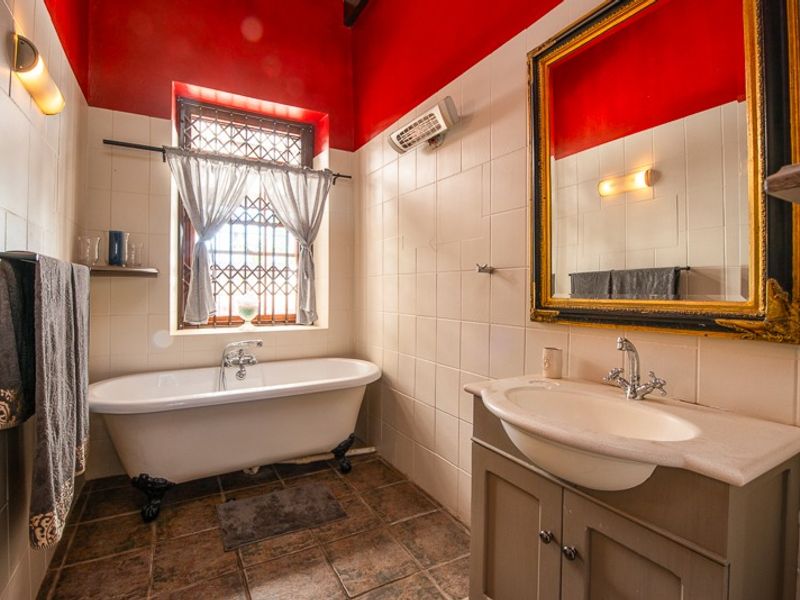 A bathroom featuring a classic clawfoot bathtub, a vanity cabinet with a basin, and tiled finishes, accented by a bold red wall.