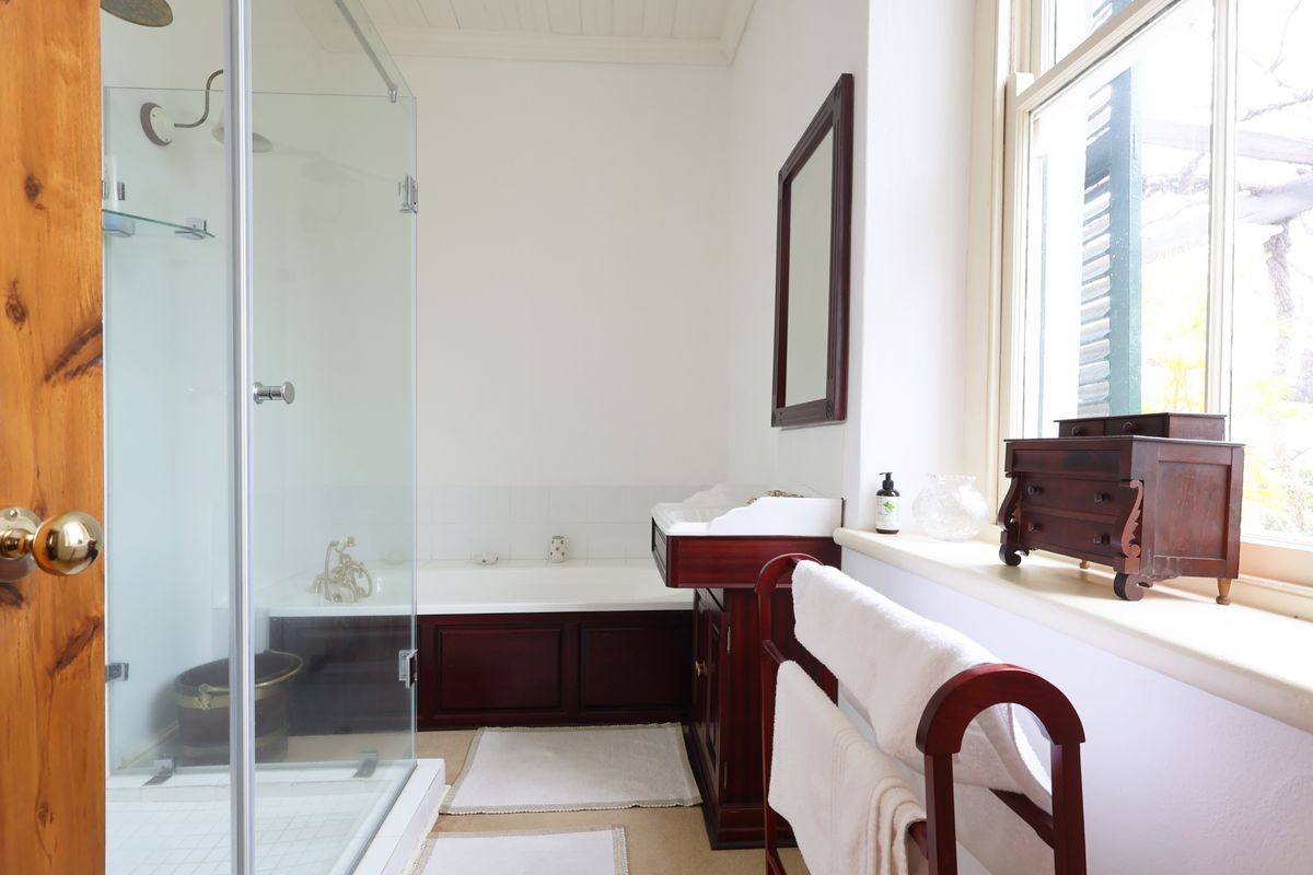 A well-maintained bathroom featuring a glass-enclosed shower, a built-in bathtub, and a classic wooden vanity cabinet with a mirror.