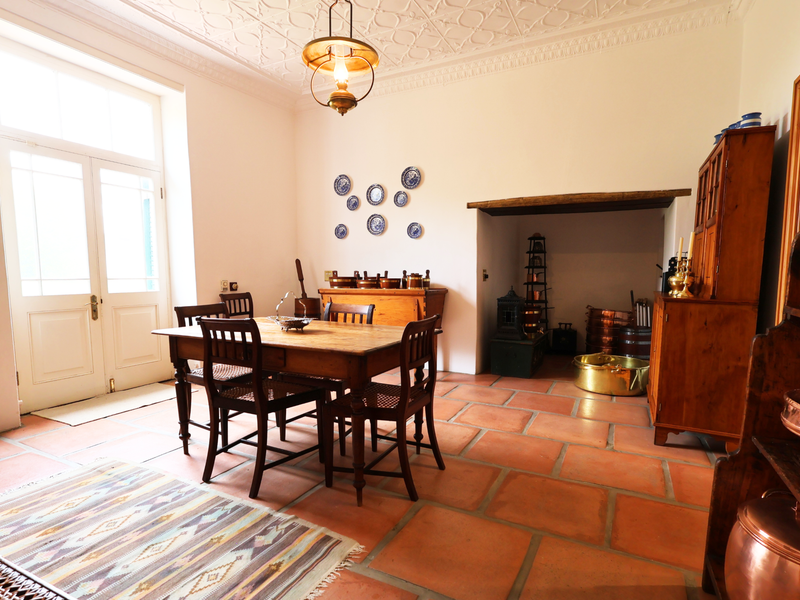 Spacious dining room featuring traditional terracotta tile flooring, an ornate plaster ceiling, and a charming recessed fireplace, offering a warm and rustic atmosphere.