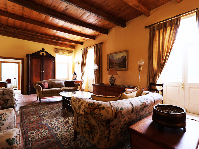 Spacious living room featuring rustic exposed timber ceiling beams, traditional terracotta floor tiles, and large double doors providing natural light.