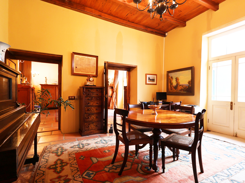 A charming dining room featuring exposed timber ceiling beams, terracotta flooring, and double glass doors providing natural light and access to the exterior.
