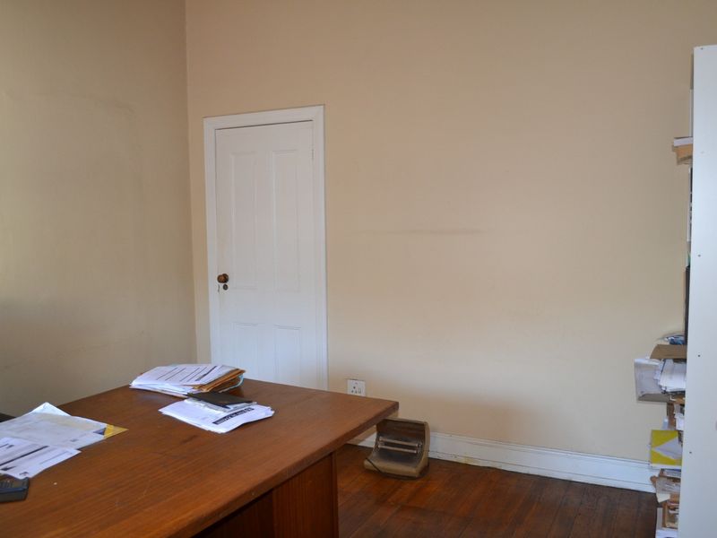 A functional office space featuring hardwood flooring and neutral wall finishes, providing a practical environment for professional use.