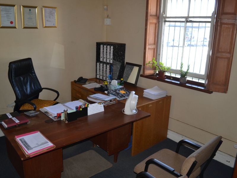 A functional office space featuring a timber-framed window with security bars and standard office finishes.