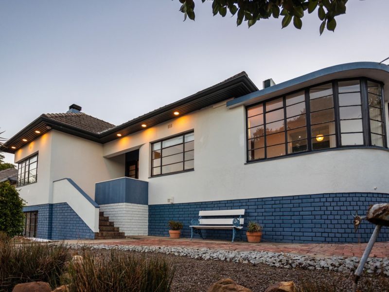 A well-maintained home featuring a distinctive curved window, blue and white brick facade, and recessed exterior lighting.